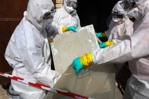 "Staff removing some asbestos in a post of transformer, Reflection of mask of man opposite was created for cannot be recognized"